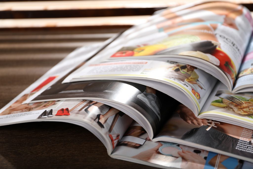 Many lifestyle magazines on wooden table, closeup