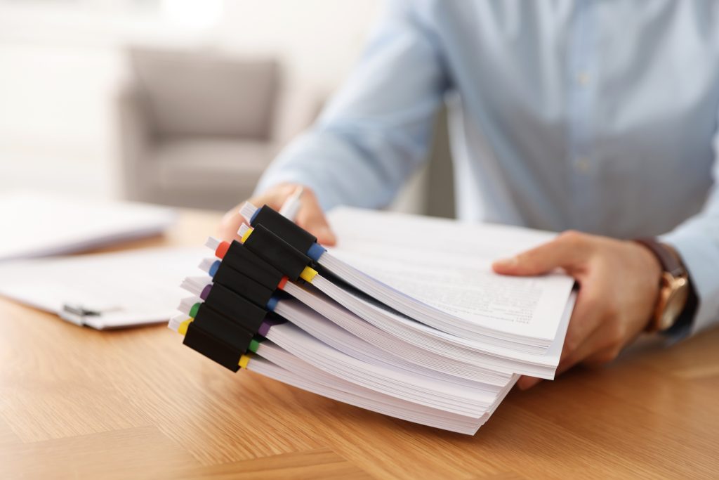 Businessman with documents at wooden table in office, closeup